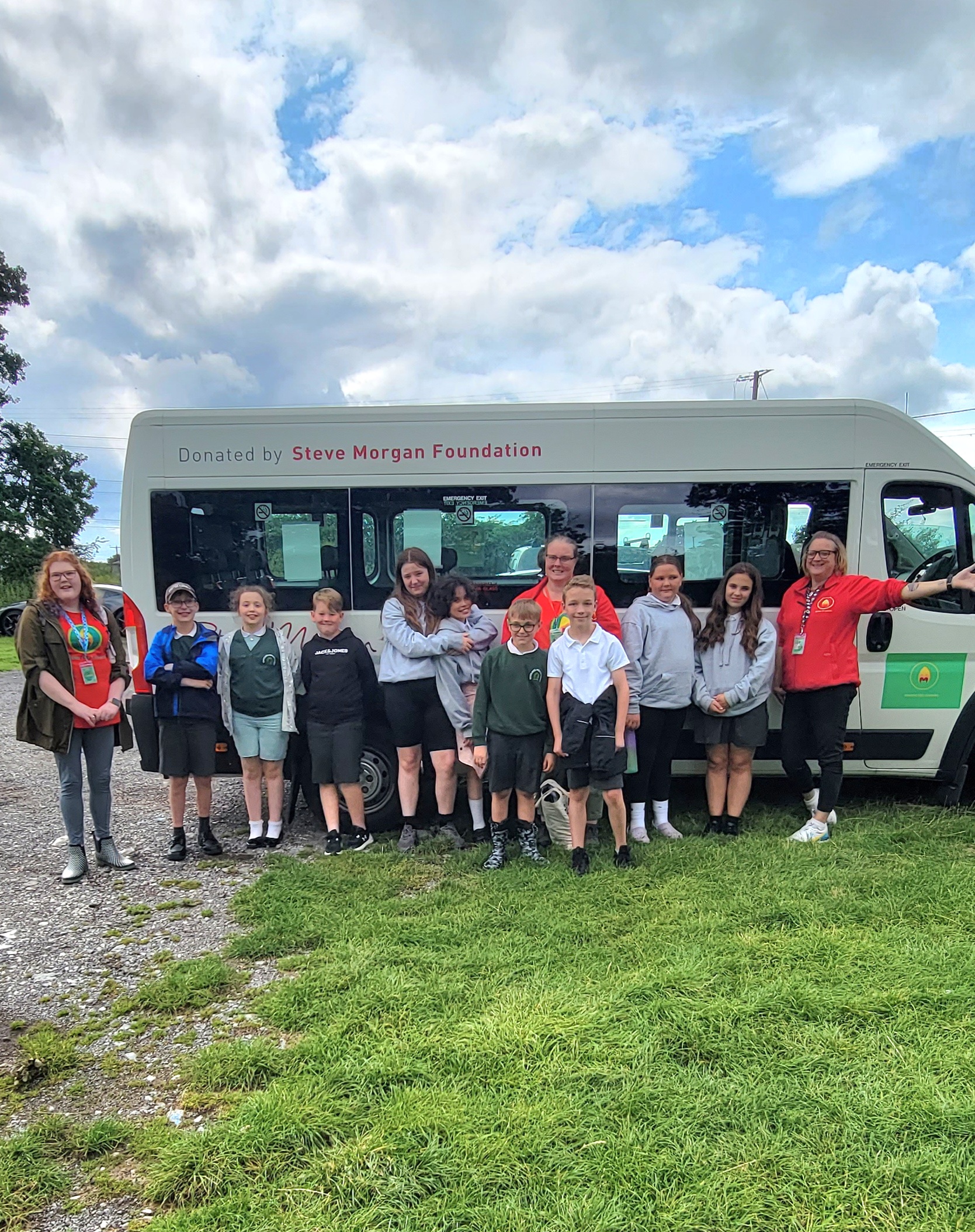 A group of school children posing outside of a Steve Morgan Foundation Minibus
