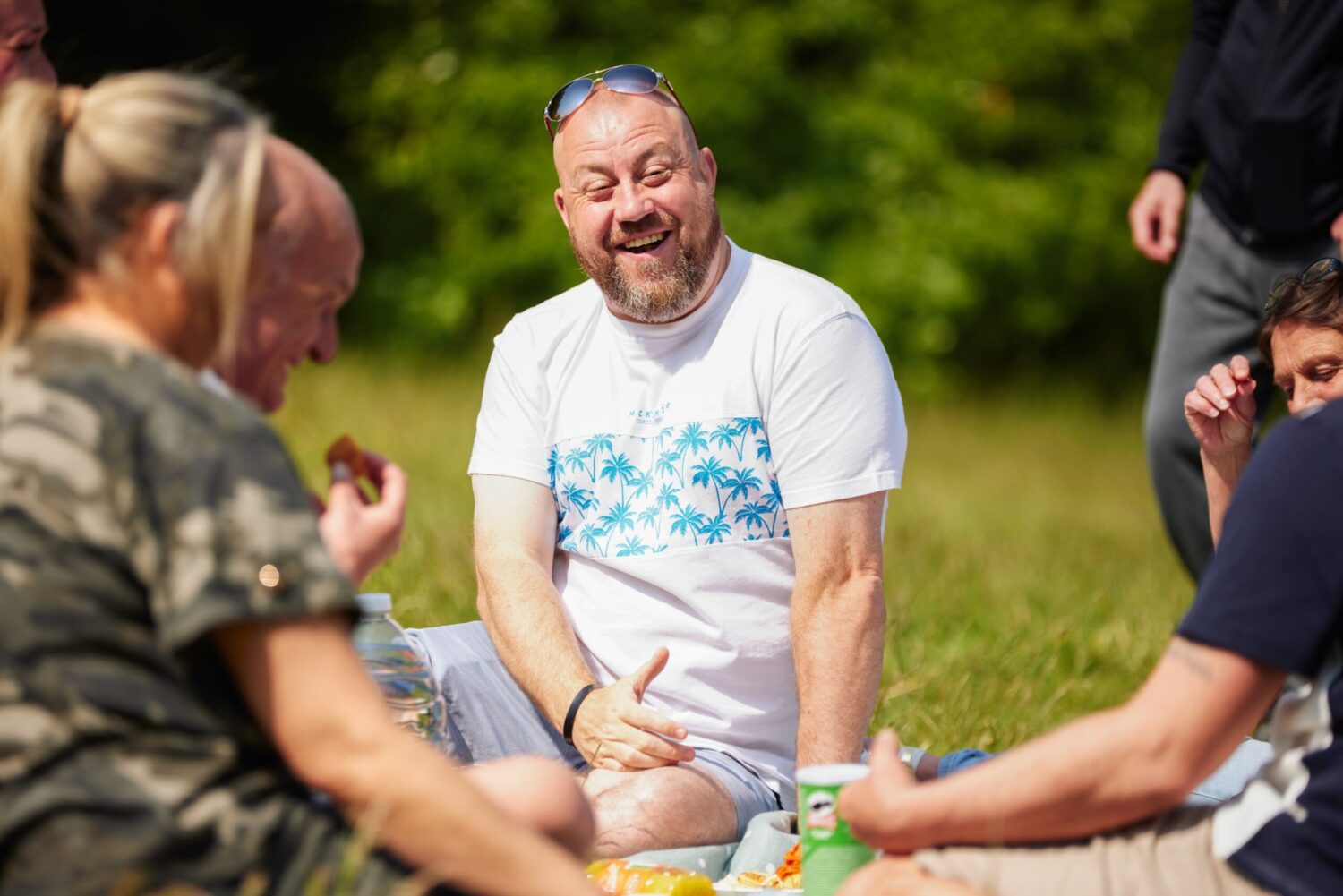 Middle aged man laughing at picnic in Sefton Park 