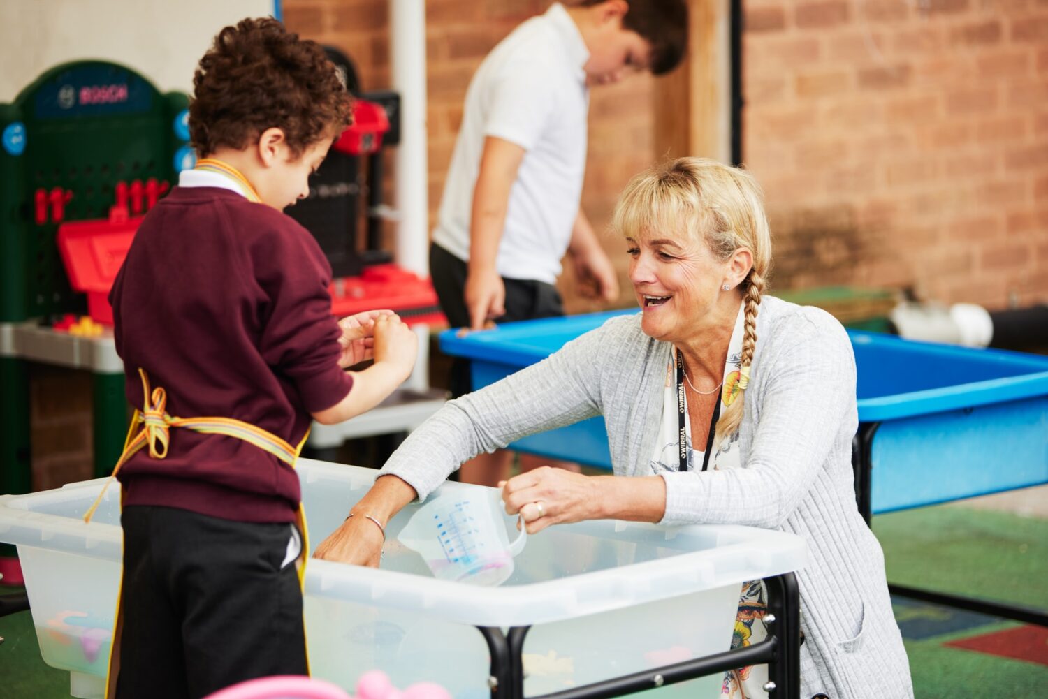 Classroom assistant and pupil enjoy play time outside 