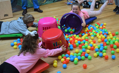 Ykids children playing hungry hippos with buckets and multicoloured balls