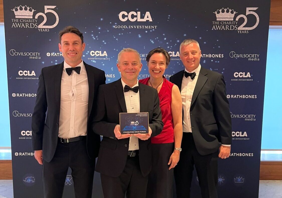 Members of the Steve Morgan Foundation with two partners on stage with an award